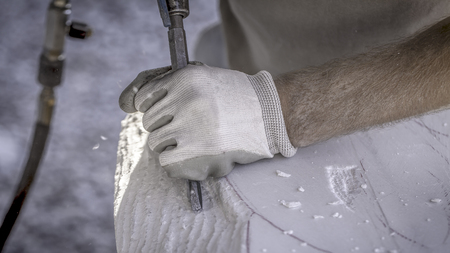 Artist working his sculpture with an electric chiselの写真素材