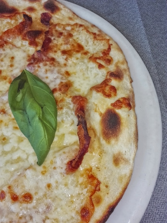 white pizza with a green basil leaf on a gray backgroundの写真素材