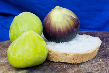 fresh tasty figs friuts on a wood plate with bread and a blue background. for healthy and natural concepts. ficus caricaの写真素材