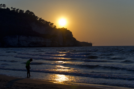 silhouette of a boy on foreshore during sunset. for vacation and summer holiday conceptの写真素材