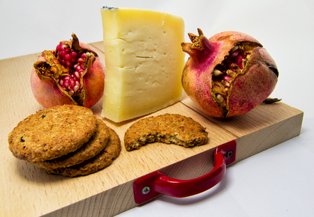 wood chopping board with assortment of cheeses, cookies and pomegranate fruit. for food conceptの写真素材