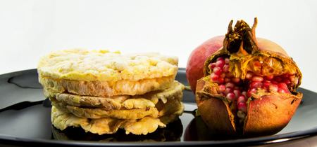 pile of rice and corn crakers with a pomegranate on a black dish. for vegetarian and healthy food conceptの写真素材