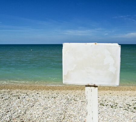 white advice panel on a beach with ocean on the background. for graphical conceptの写真素材