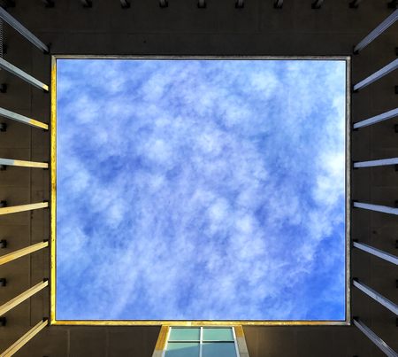 Blurred sky and clouds seen through a square window used as background.の写真素材
