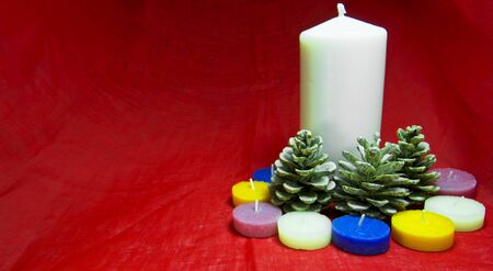 Christmas decorations with candles, pine cone and nut on a red background. Copy space available. For Xmas conceptの写真素材