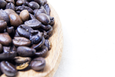 close up of roasted coffee beans on a wood spoon with white background with space for text. の写真素材