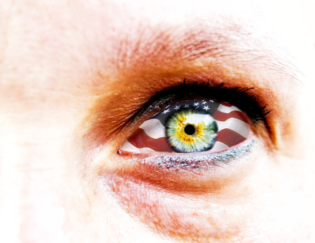 soft focus and close up of a green yellow woman eye isolated on a white background with usa flag in the irisの写真素材