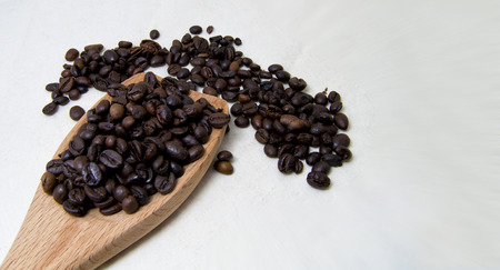 close up of roasted coffee beans on a wood spoon with white background with space for text. の写真素材