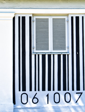 black and white barcode painted on a house wall with a window in the middleの写真素材