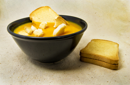 delicious pumpkin pured soup with potatoes and zwiebacks bread slices. for vegetarian, vegan and healthy conceptの写真素材