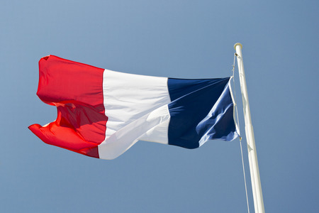 French flag waving in the wind with blue sky as background.の写真素材