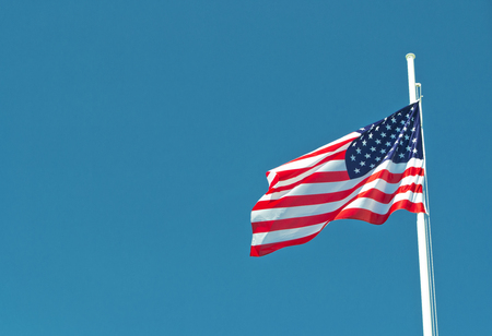 usa flag waving in the wind with blue sky as background.の写真素材