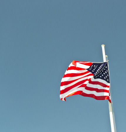 usa flag waving in the wind with blue sky as background.の写真素材