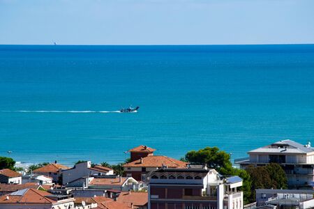 Fishing boat returning in port of Giulianova, Abruzzo, Italy. With shoreline and offshore gas extraction platformの写真素材