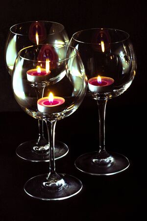 three candels tealights in wine glasses. romantic atmosphere and spa conceptsの写真素材