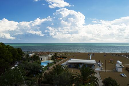 Summer concept: mediterranean italian beach with sand and parasols, cloudy sky, nobody present.の写真素材