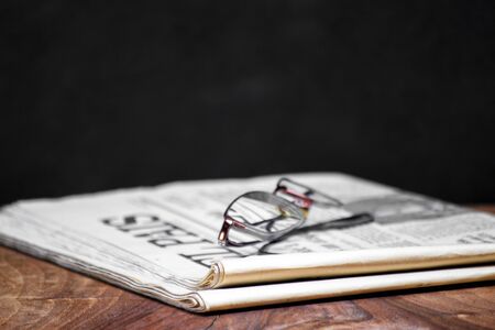 folded newspaper with a pair of reading glasses on it. free information and press concept