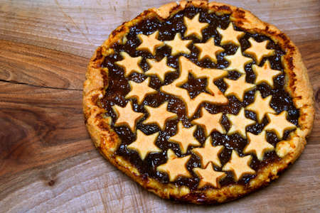 homemade plum jam tart pie on a wooden chopping board with stars shortcrust pastry decorations. Food conceptの写真素材