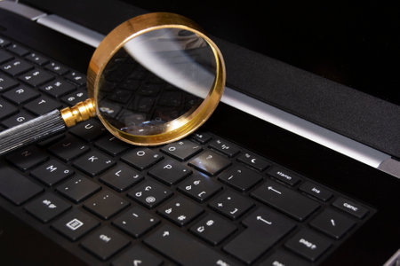 Magnifying glass on mobile laptop keybord, searching information, enlarge knowledge or inspect...