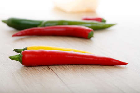 colored chili peppers on a wooden surface