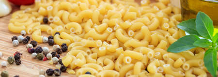 Raw macaroni pasta with pepper and basilの写真素材