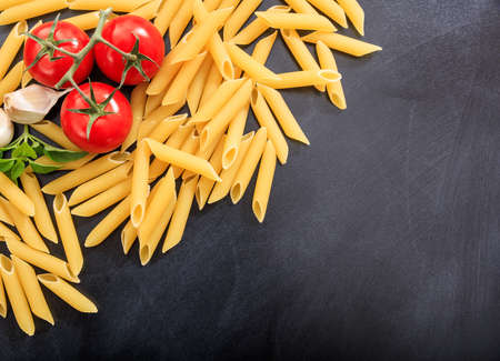 Raw penne on black background
