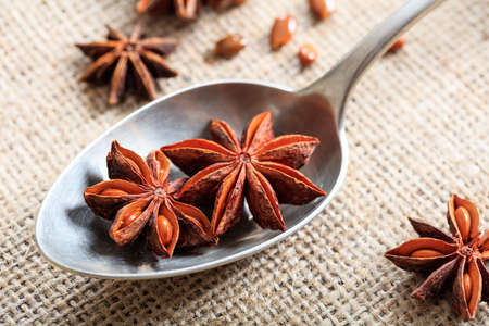 Dried star anise in a spoon on a sackclothの写真素材