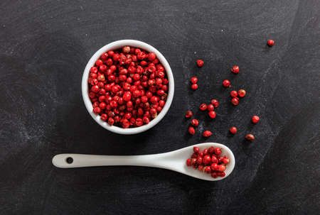 Red pepper spice seeds in porcelain bowl and spoon, black backgroundの写真素材