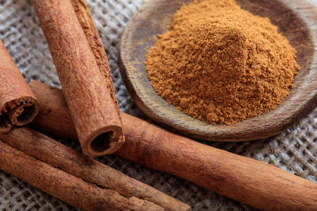 Cinnamon sticks and powder on a sackclothの写真素材