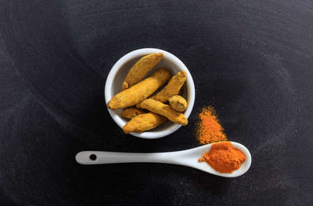 Turmeric in porcelain bowl and spoon, black backgroundの写真素材