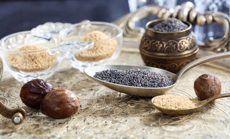 Yellow and brown poppy seeds in spoonsの写真素材