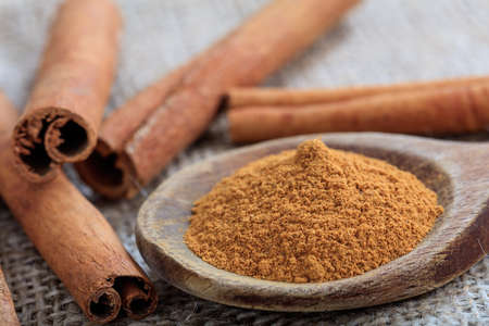 Cinnamon sticks and powder on a sackclothの写真素材