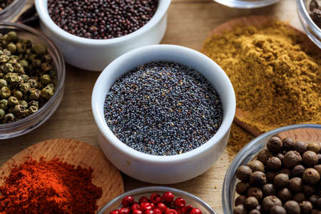 Poppy seeds and other spices on a wooden surfaceの写真素材