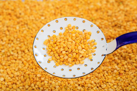 Metallic spoon on raw split peas background