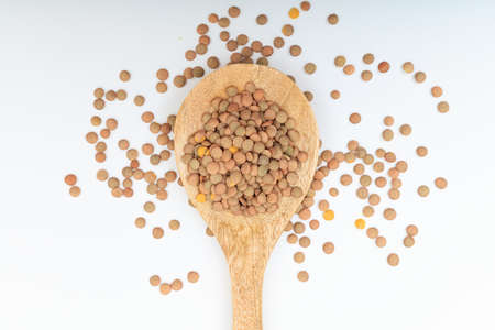 Raw lentils in a wooden spoon on white backgroundの写真素材