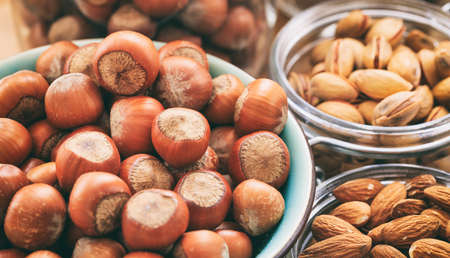 Hazelnuts, almonds and pistachios in bowlsの写真素材