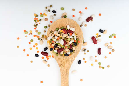 Mixed legumes in a wooden spoon on white backgroundの写真素材