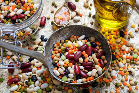 Old metallic spoon and mixed raw legumes