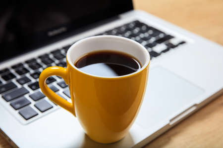 Cup of coffee and a laptop on an office tableの写真素材