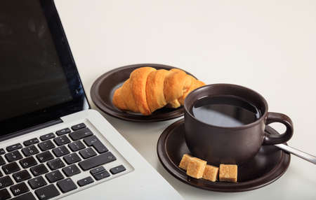 Cup of coffee and a laptop on a office tableの写真素材