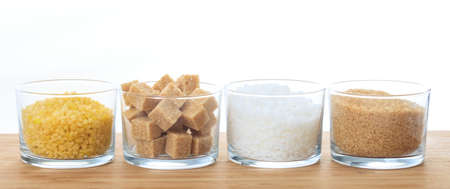 Various types of sugar in glass bowls on a tableの写真素材