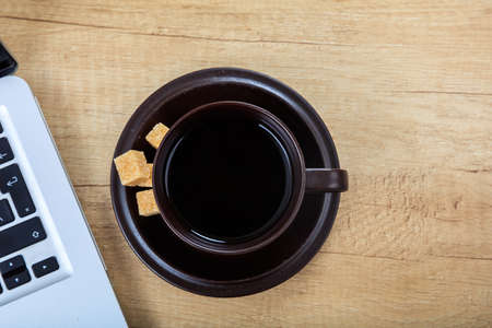 Cup of coffee and a laptop on a office tableの写真素材