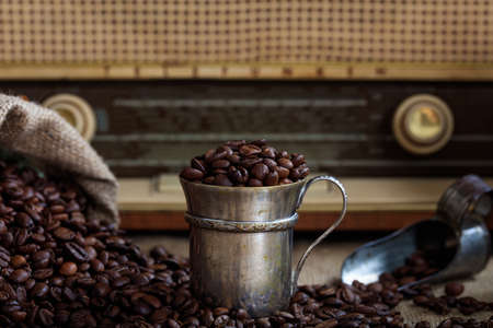 Cup with coffee beans infront of an old radioの写真素材