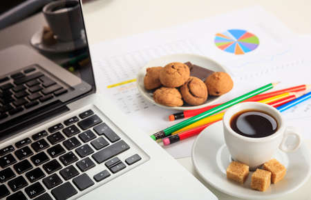 Office desk with laptop and a cup of coffeeの写真素材