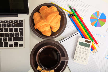 Office desk with laptop and a cup of coffeeの写真素材