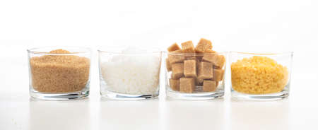 Various types of sugar in glass bowls on white backgroundの写真素材