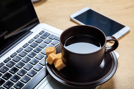 Cup of coffee and a laptop on a office tableの写真素材