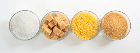 Various types of sugar in glass bowls on white backgroundの写真素材