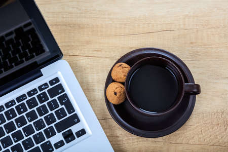 Cup of coffee and a laptop on a office tableの写真素材