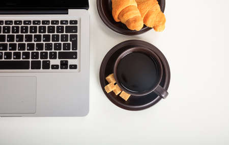 Cup of coffee and a laptop on a office tableの写真素材